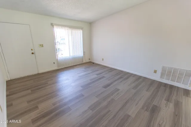 an empty room with wooden floor and windows