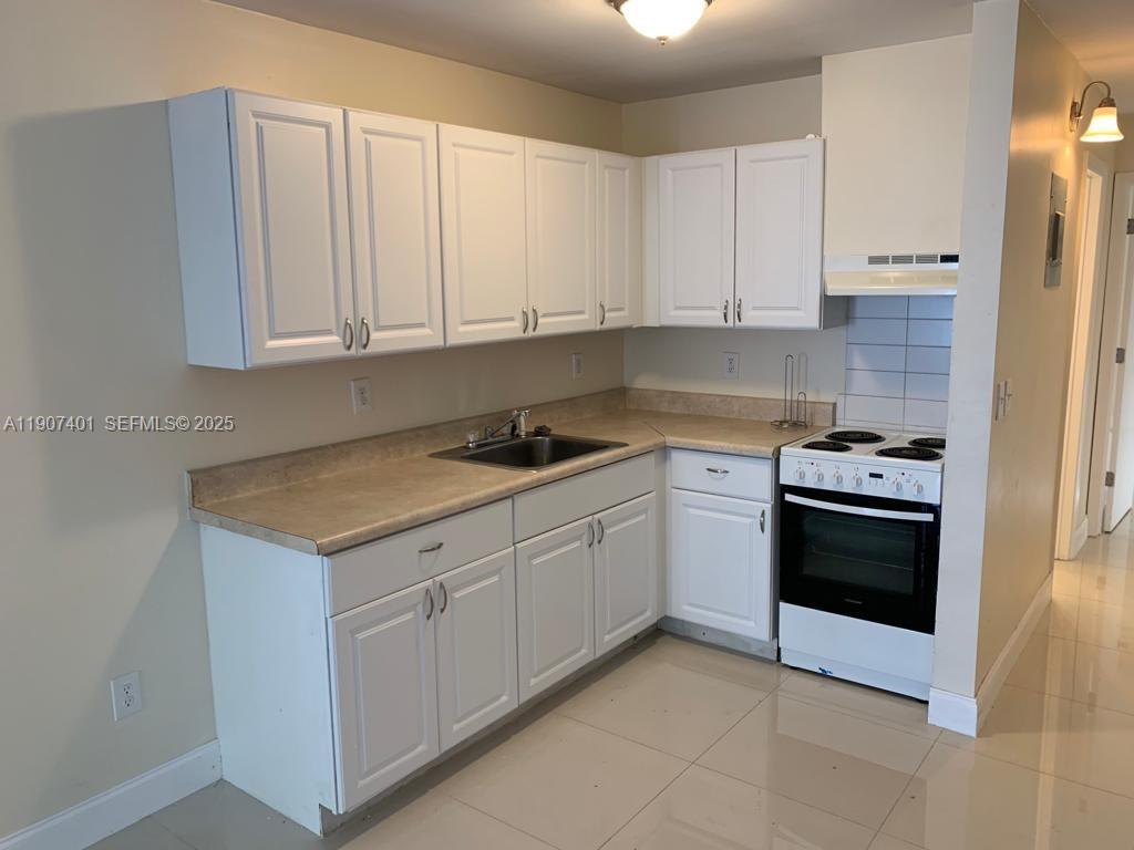 1511 Northeast 117th Street, Unit 2 Miami, FL 33161 - Photo 6 of 14 a kitchen with granite countertop white cabinets and stainless steel appliances