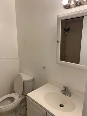 a bathroom with a toilet sink vanity and mirror