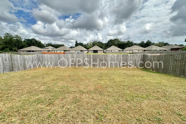 a view of a back yard of the house and a wooden fence