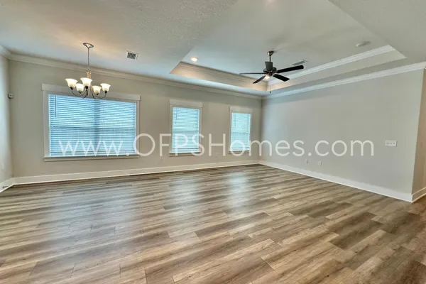 a view of an empty room with wooden floor and a ceiling fan