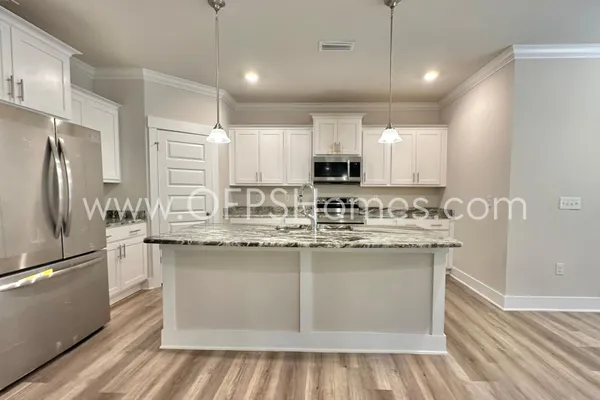 a kitchen with kitchen island granite countertop a sink cabinets and stainless steel appliances