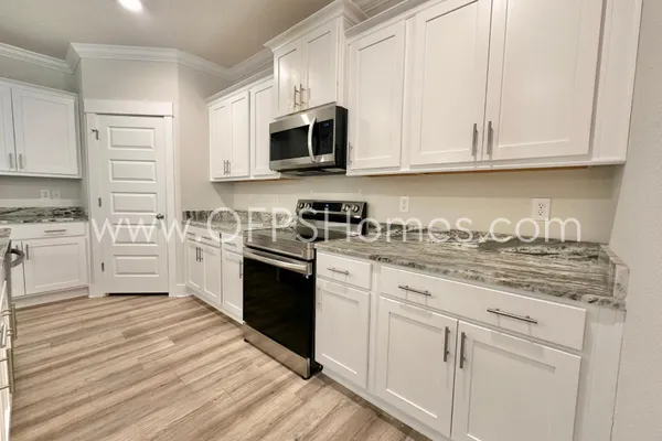 a kitchen with granite countertop white cabinets and stainless steel appliances