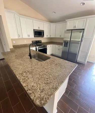 a kitchen with stainless steel appliances granite countertop a sink stove and refrigerator