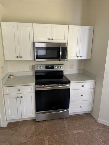 a kitchen with granite countertop white cabinets and stainless steel appliances