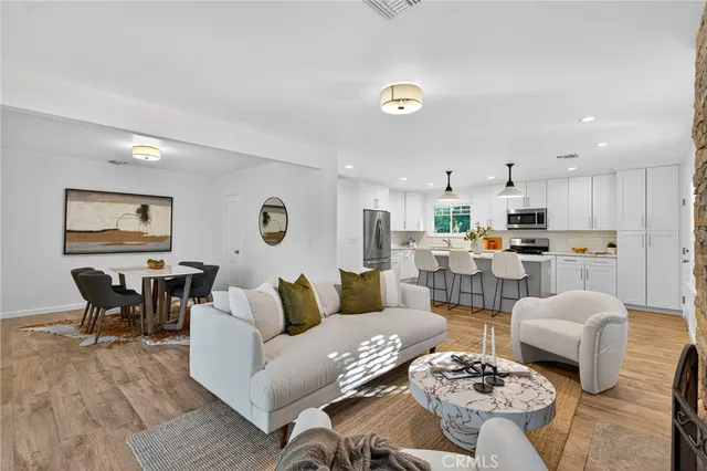 a kitchen with stainless steel appliances granite countertop a dining table chairs refrigerator and microwave