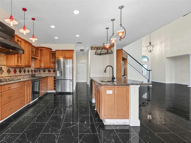 a kitchen with granite countertop a stove a sink and a refrigerator