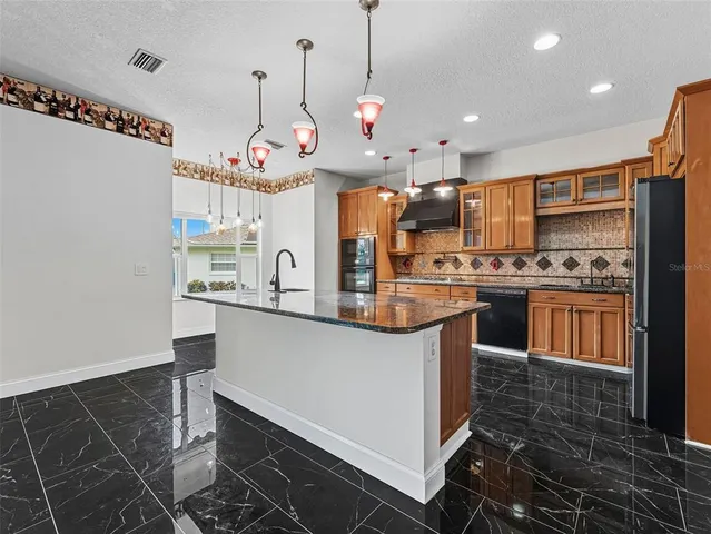 a kitchen with stainless steel appliances a dining table chairs sink and cabinets