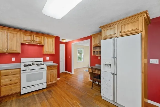 a kitchen with a stove a refrigerator and wooden floor