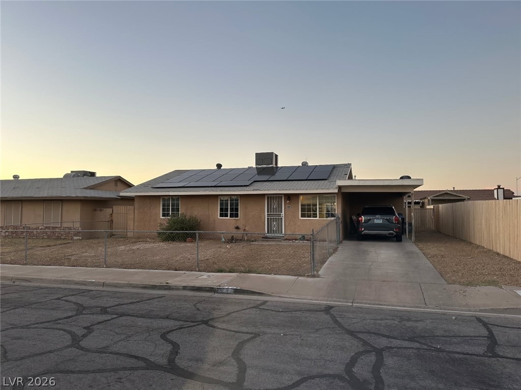 233 Ash Street Henderson, NV 89015 - Photo 14 of 20 Ranch-style home featuring a carport, stucco siding, roof mounted solar panels, a fenced front yard, and concrete driveway