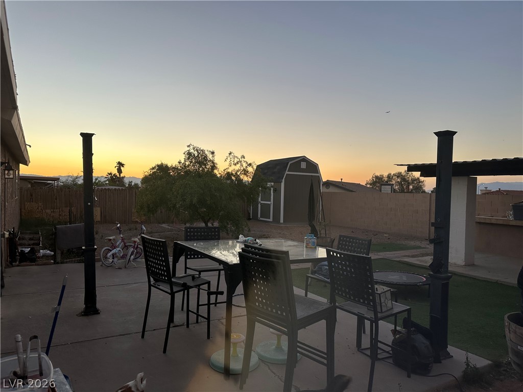 233 Ash Street Henderson, NV 89015 - Photo 16 of 20 Fenced backyard featuring a storage unit, a patio, and outdoor dining space