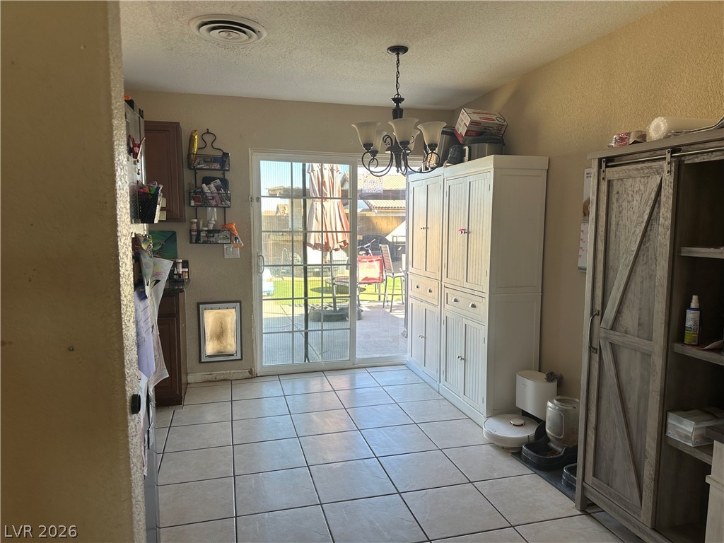 233 Ash Street Henderson, NV 89015 - Photo 4 of 20 Unfurnished dining area with suspended lighting, a textured ceiling, light tile patterned floors, and a barn door