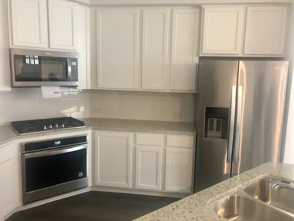 a kitchen with stainless steel appliances granite countertop a refrigerator stove and white cabinets