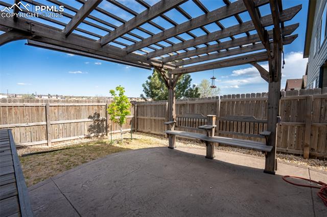1985 Reed Grass Way Colorado Springs, CO 80915 - Photo 29 of 36 Backyard with stamped concrete, pergola, and fire pit