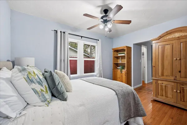 a bedroom with a large bed dresser and wooden floor