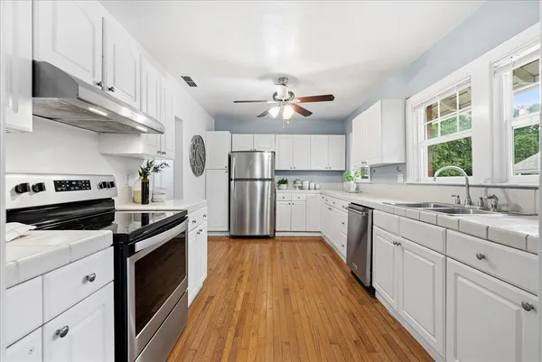 a kitchen with white cabinets appliances and a window