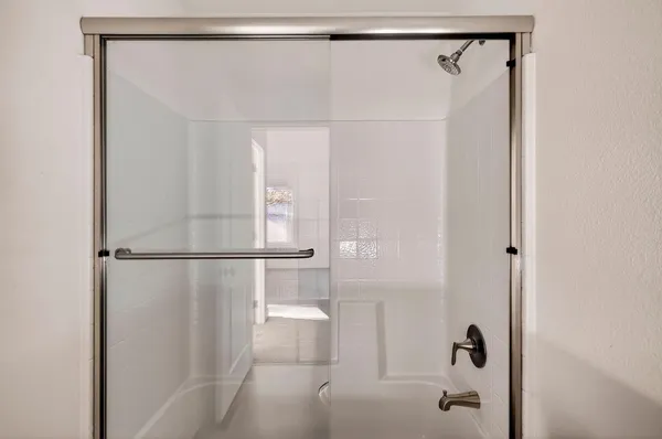 a view of a hallway with wooden floor and a bathroom