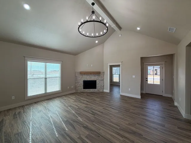 an empty room with wooden floor fireplace and windows