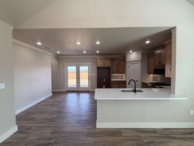 a large kitchen with a sink a counter top space stainless steel appliances and a window