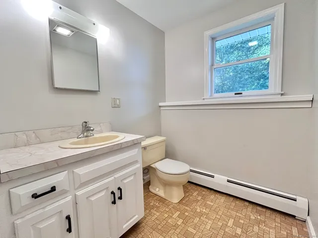 a bathroom with a granite countertop toilet and a sink