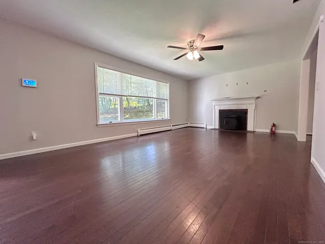 an empty room with wooden floor fireplace and windows