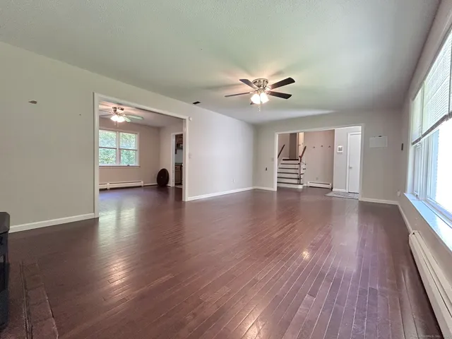 a view of an empty room with a window and wooden floor