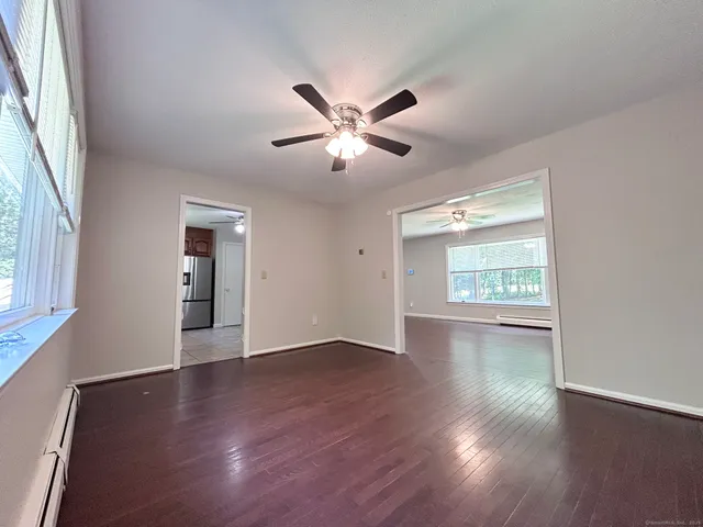 a view of an empty room with window and wooden floor
