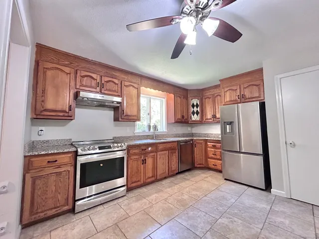 a kitchen with stainless steel appliances granite countertop a refrigerator a sink dishwasher a stove with wooden cabinets