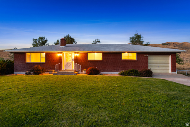 1940 West Old Hwy Road Morgan, UT 84050 - Photo 4 of 73 Brick ranch-style residence featuring a single-car garage with a roll-up door, a concrete driveway, and a front porch with white railings