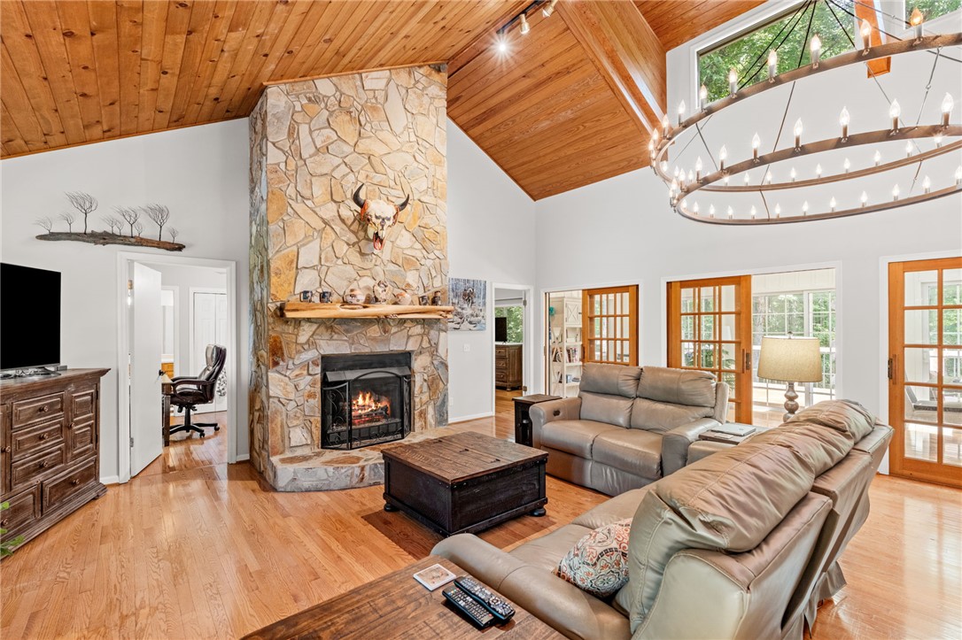 Rich wood plank ceilings and a soaring stone fireplace ground this open living area.