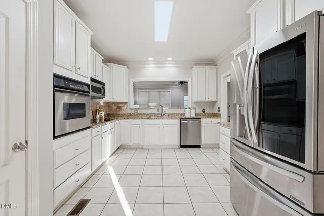 a kitchen with stainless steel appliances granite countertop a refrigerator a sink a stove top oven and cabinets
