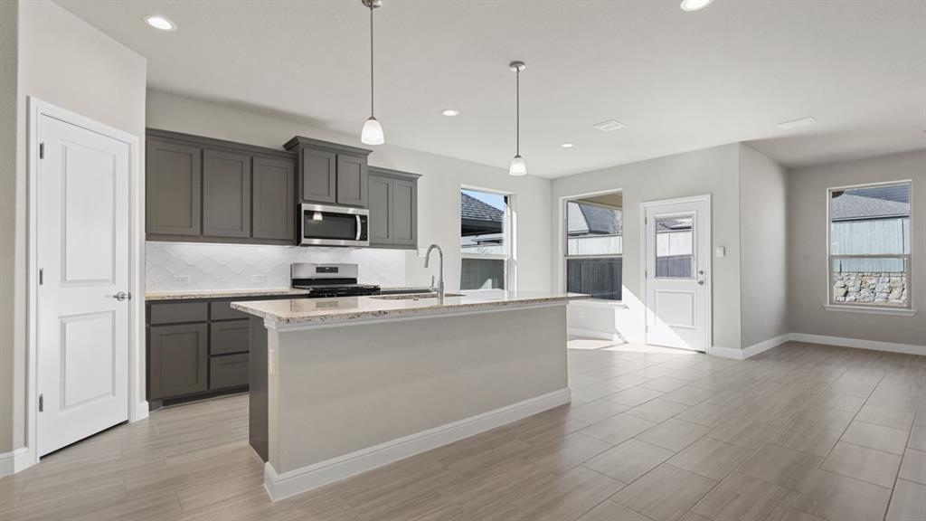 11409 Treehouse Trail Justin, TX 76247 - Photo 37 of 39 a kitchen with stainless steel appliances granite countertop a refrigerator a sink dishwasher a stove and white cabinets with wooden floor