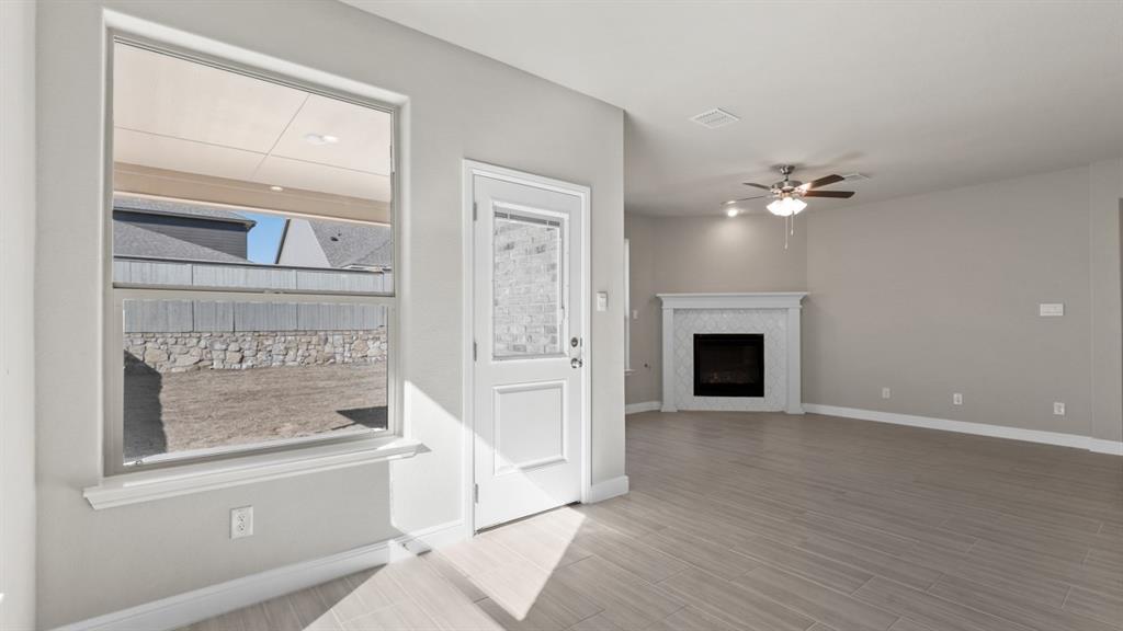 11409 Treehouse Trail Justin, TX 76247 - Photo 4 of 39 an empty room with wooden floor fireplace and windows