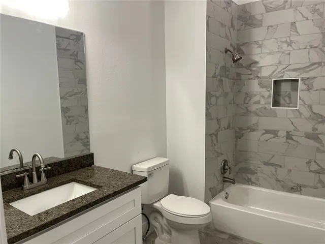 a bathroom with a granite countertop sink toilet and shower