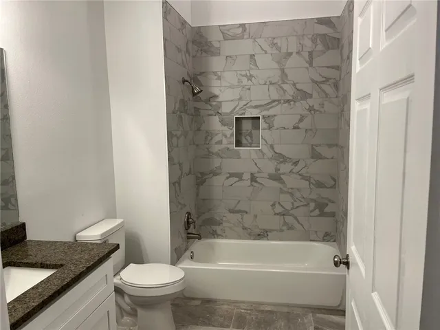 a bathroom with a granite countertop toilet a sink and bathtub