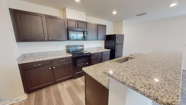 a kitchen with stainless steel appliances granite countertop a kitchen island a stove and a sink