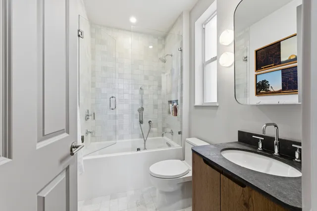 a bathroom with a granite countertop sink toilet mirror and bathtub