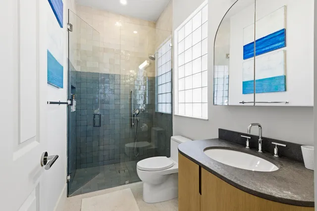 a bathroom with a granite countertop sink a toilet a mirror and shower