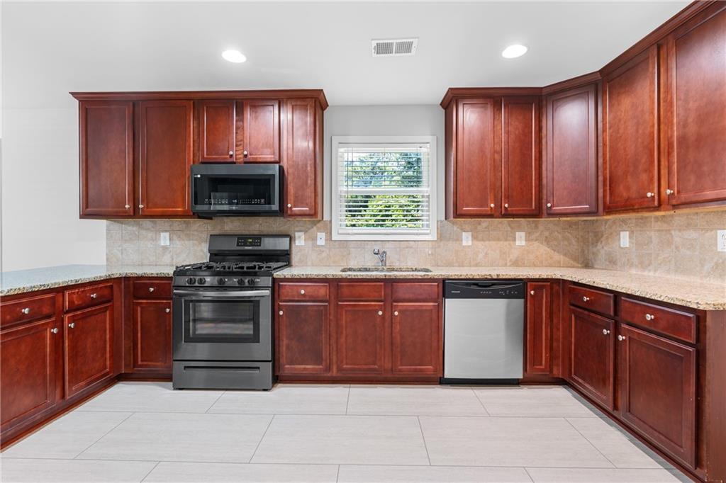 3159 Robinson Avenue Scottdale, GA 30079 - Photo 14 of 45 a kitchen with stainless steel appliances granite countertop wooden cabinets a stove top oven a sink and dishwasher