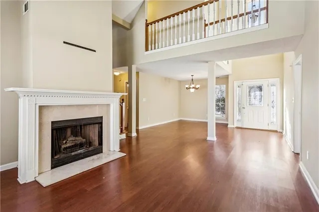 a view of an empty room with wooden floor fireplace and a window