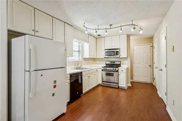 a kitchen with cabinets stainless steel appliances and wooden floor