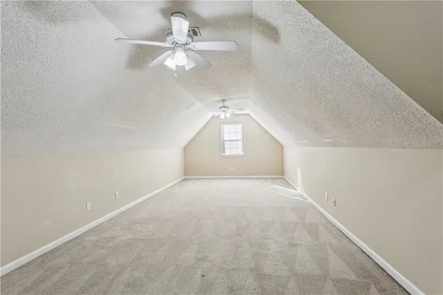 an empty room with a chandelier fan and windows