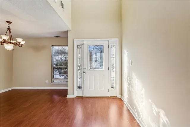 an empty room with wooden floor chandelier and windows