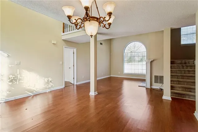 a view of an empty room with wooden floor and a chandelier