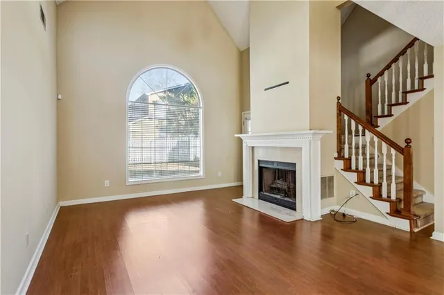 a view of an empty room with wooden floor fireplace and a window