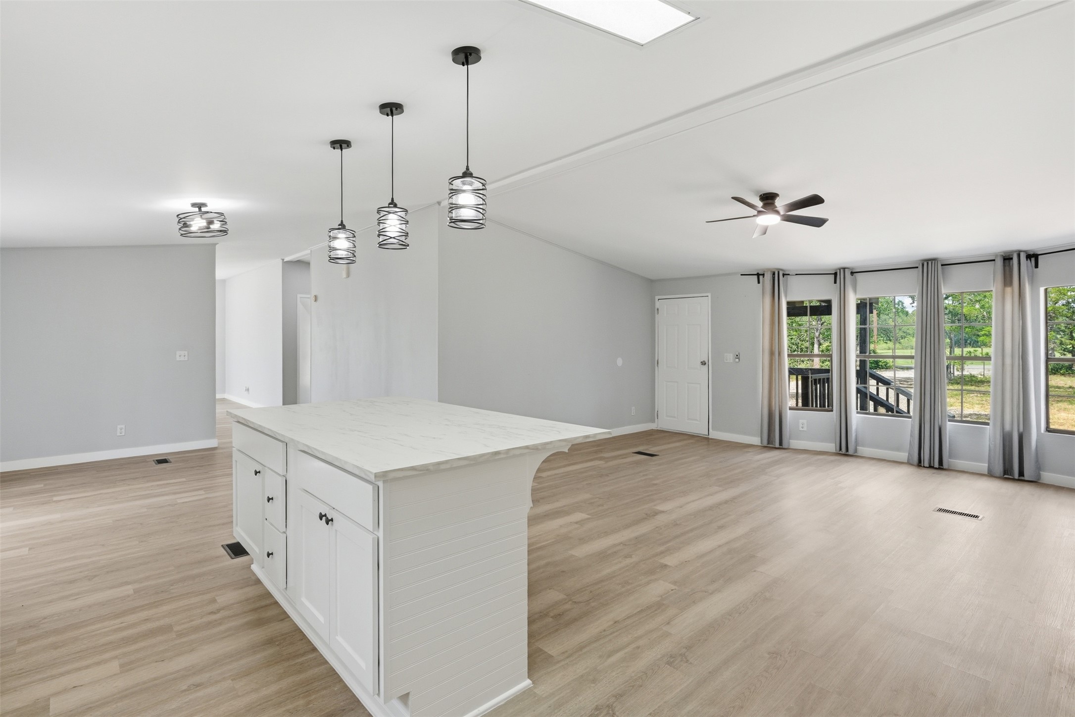 154 Antioch Road Smithville, TX 78957 - Photo 11 of 32 A well-lit interior features a modern kitchen island, wood flooring, and ample natural light through multiple windows.
