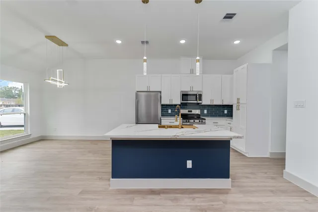 a view of kitchen with kitchen island stainless steel appliances a sink and wooden floor