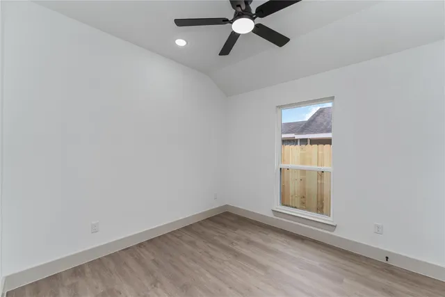 an empty room with a window and ceiling fan