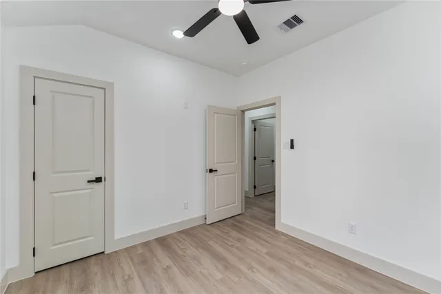 an empty room with wooden floor and ceiling fan