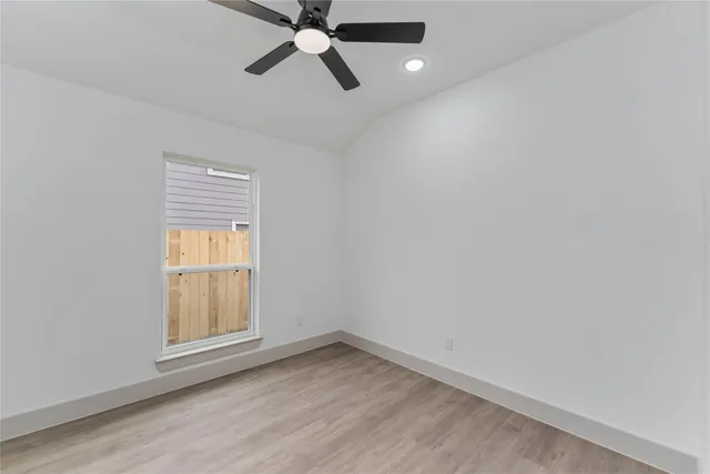 an empty room with a window and ceiling fan